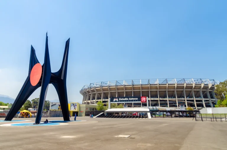 Exterior view of Estadio Azteca stadium in Mexico City with sculpture in foreground
