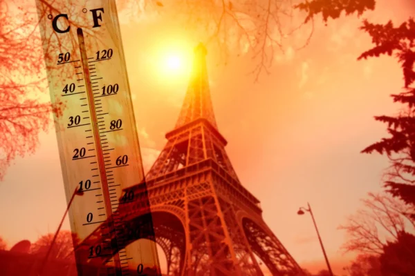 Eiffel Tower in Paris during a heatwave with thermometer showing extreme high temperatures.
