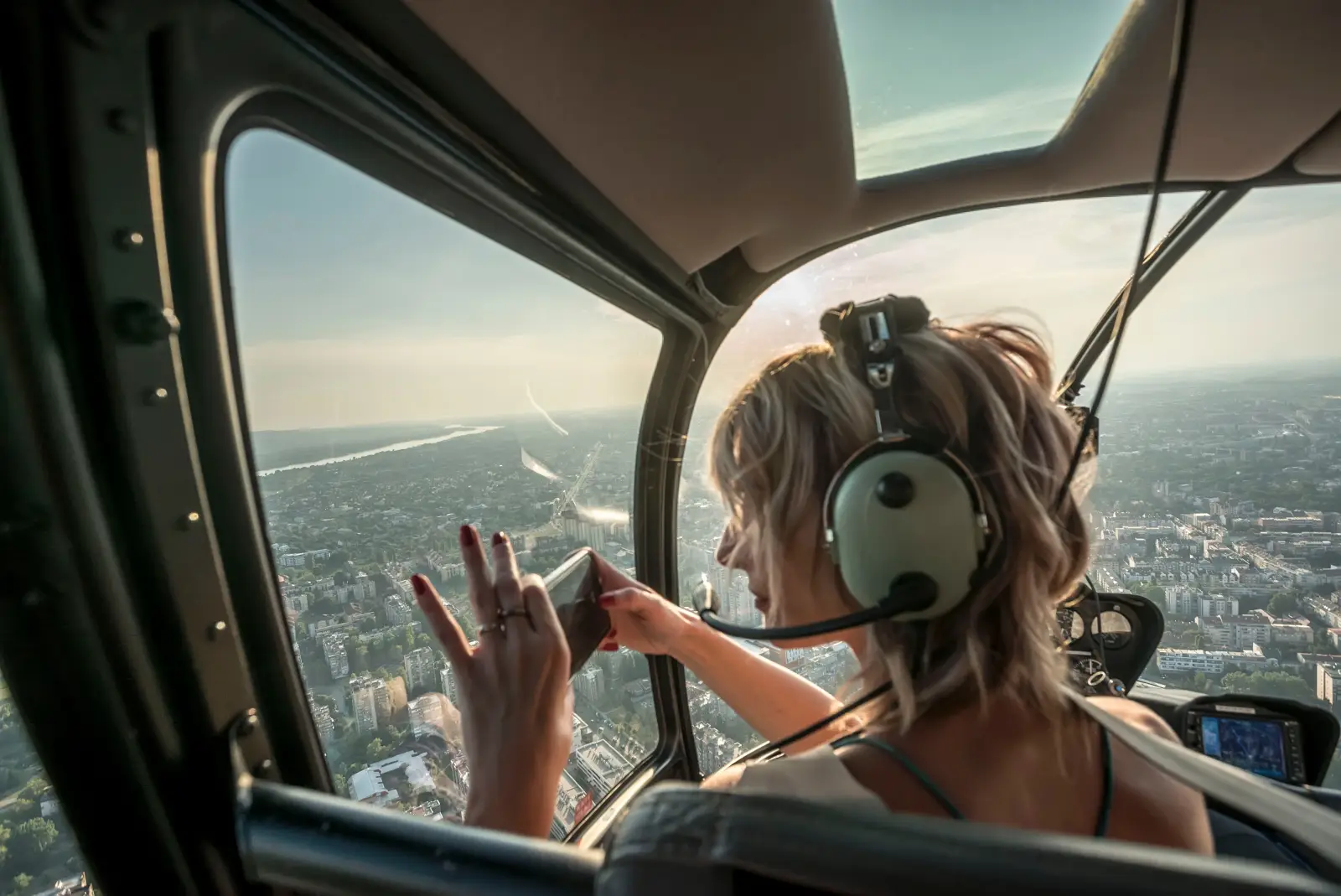 Woman taking photo from helicopter with headset on during flight