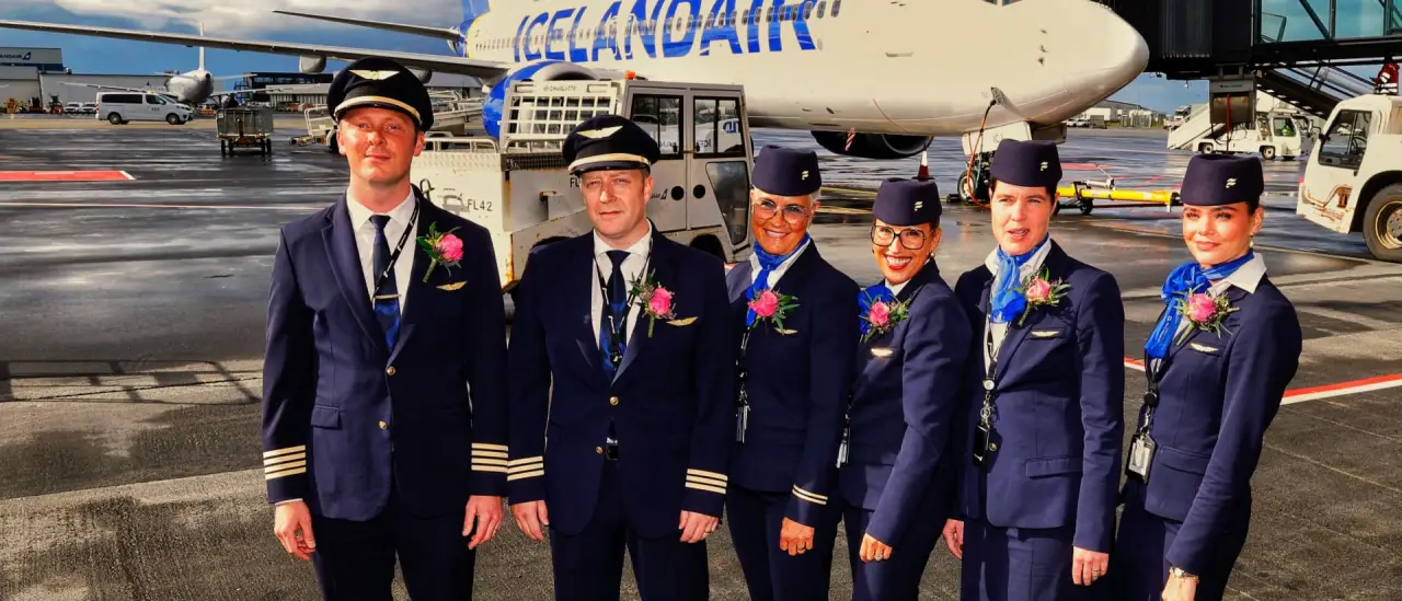 Icelandair pilots and cabin crew in uniform posing in front of an aircraft on the tarmac