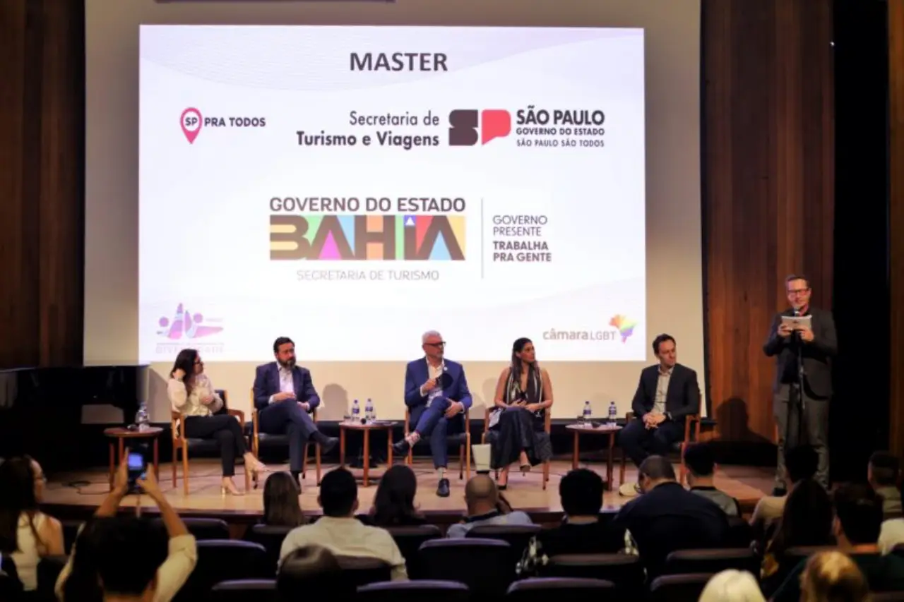 Panel discussion at the International Diversity Conference in São Paulo with tourism and business leaders seated on stage before a projected screen of event sponsors.