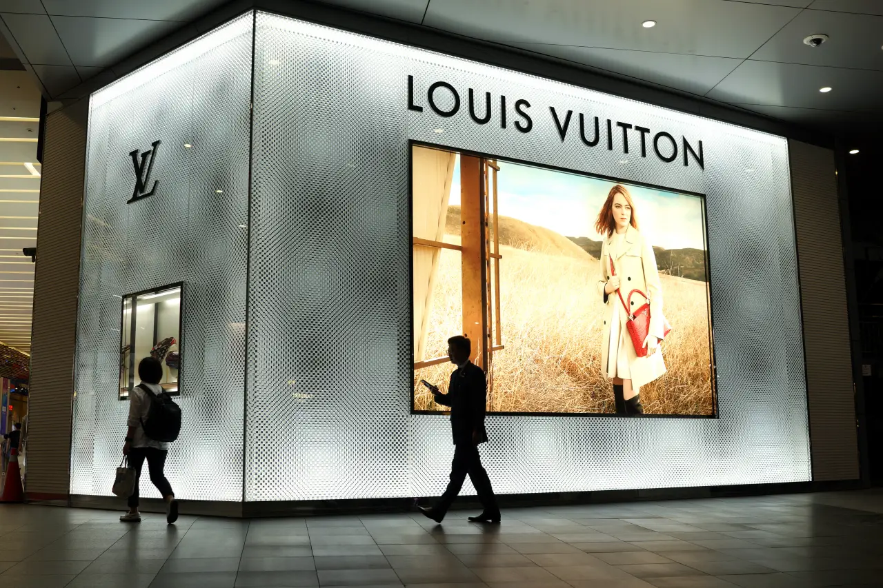 Louis Vuitton storefront with illuminated display and people walking by