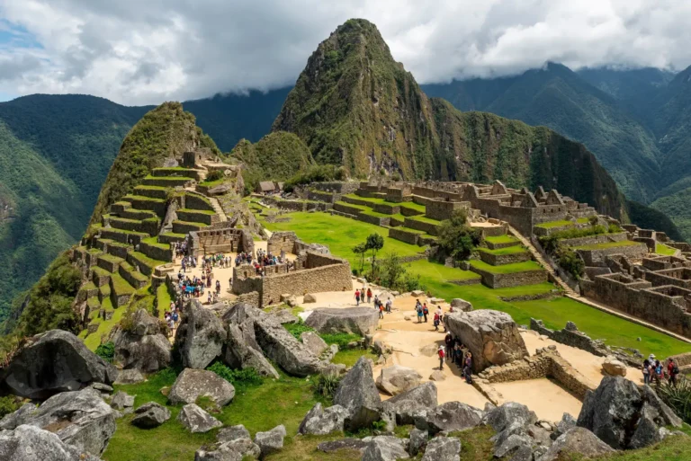 Tourists exploring the ancient Inca citadel of Machu Picchu in the Andes mountains of Peru