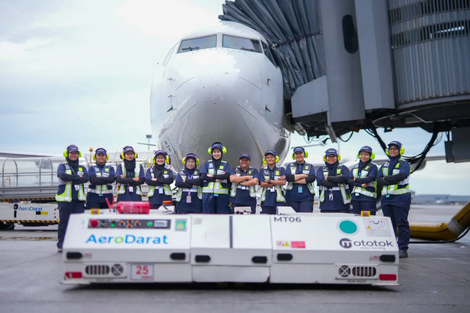 Todas las femeninas de la tripulación de tierra de las aerolíneas de Malasia parados frente a un avión de puerta