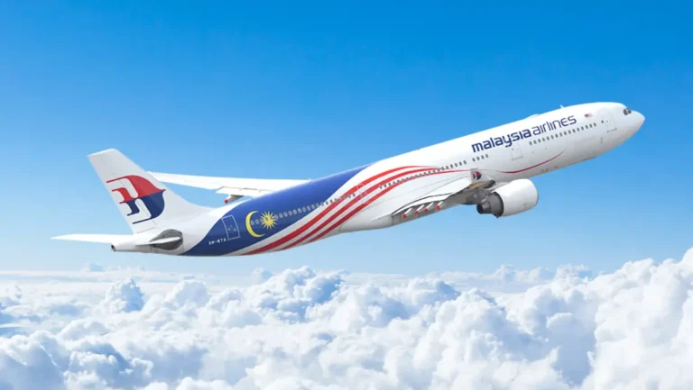 Malaysia Airlines aircraft with national flag livery flying above the clouds