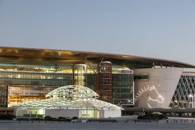 Luxury Travel 31 Exterior view of Meydan Racecourse in Dubai at dusk, featuring modern architecture and illuminated horse head design on the building.