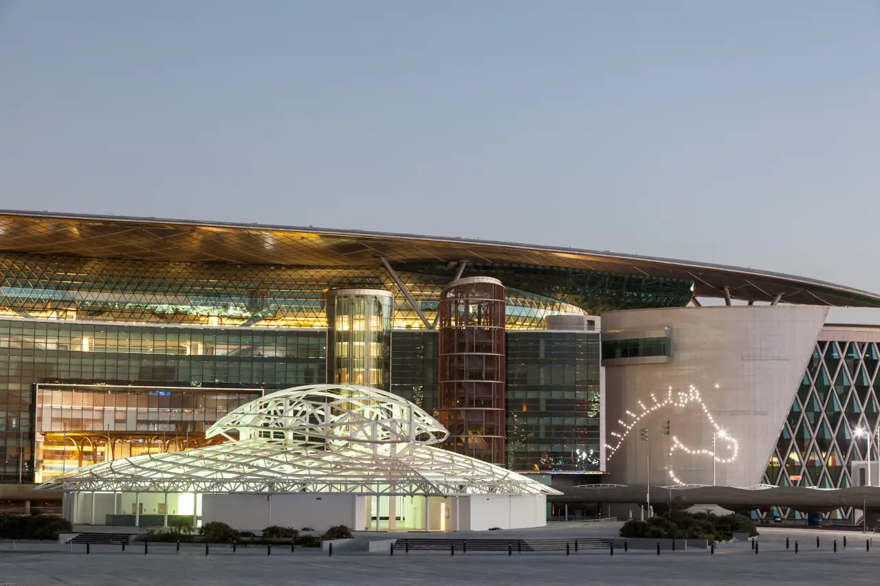 Why Horse Racing Remains A Key Attraction For Luxury Travelers 2 Exterior view of Meydan Racecourse in Dubai at dusk, featuring modern architecture and illuminated horse head design on the building.