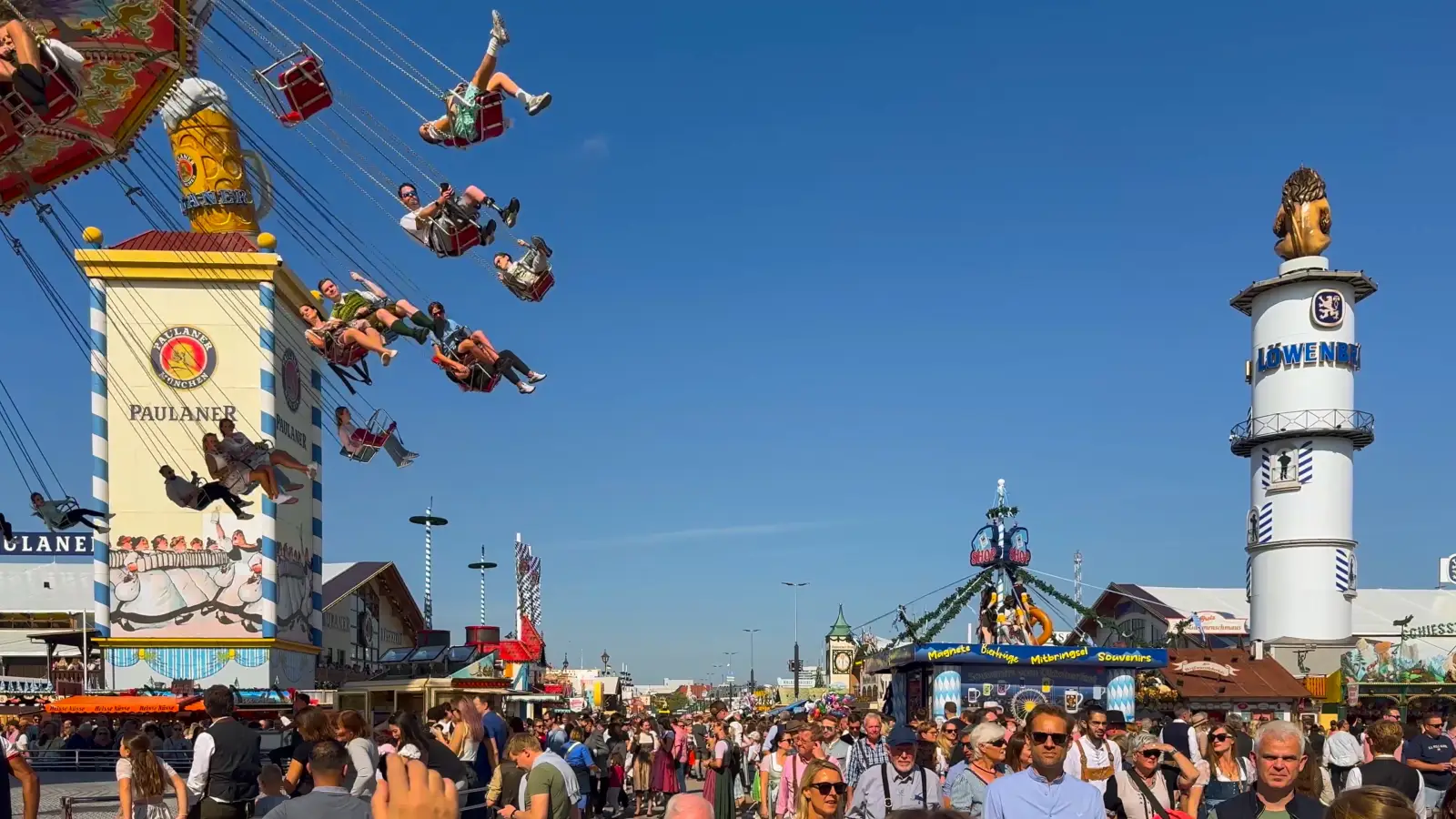 Crowds at Munich Oktoberfest with people on swing ride and brewery towers
