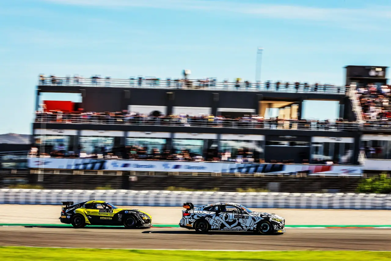 Racing cars compete on track at Circuit Ricardo Tormo with grandstands full of spectators.