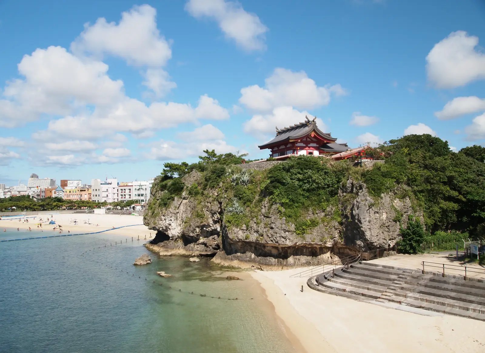Beachfront temple on rocky cliff overlooking sandy shore and clear waters in Okinawa, Japan
