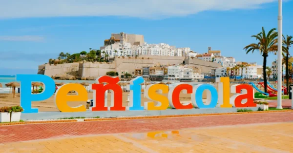 Colorful Peñíscola sign on the beach with the historic castle and old town in the background