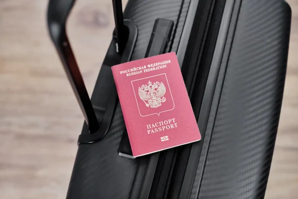 Home 7 Russian passport placed on a black suitcase handle, symbolizing international travel.