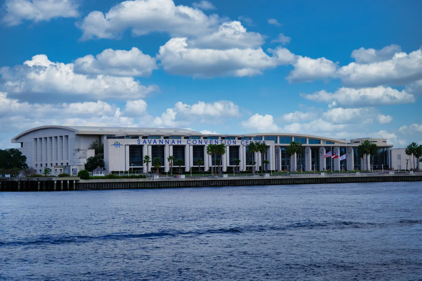 Savannah Convention Center building viewed from across the river under a blue sky with clouds.