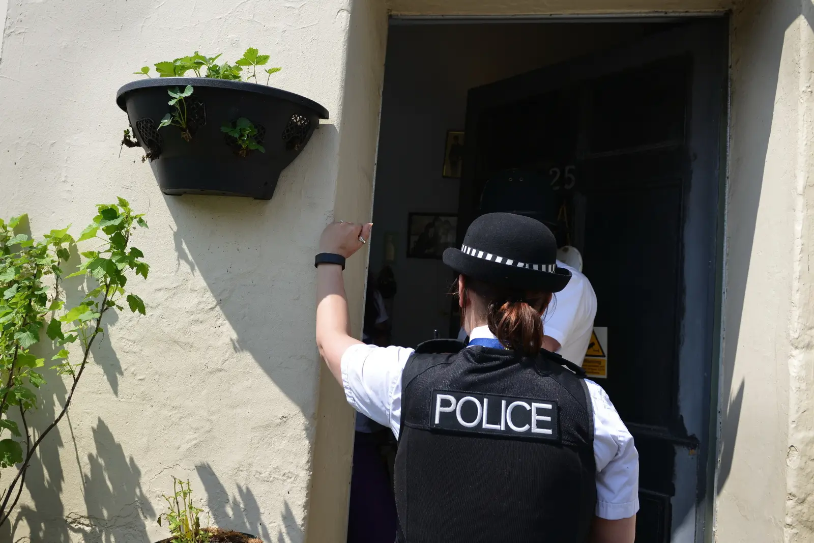 UK police officer knocks on a front door during a visit