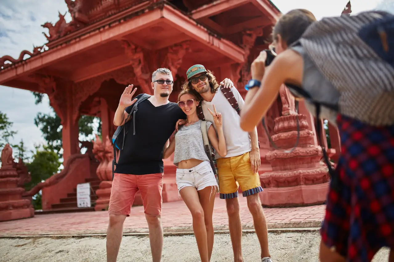 Protect Yourself In Thailand: U.s. Expat Insurance Guide 11 U.S. expat tourists posing for a photo at a red temple in Thailand.