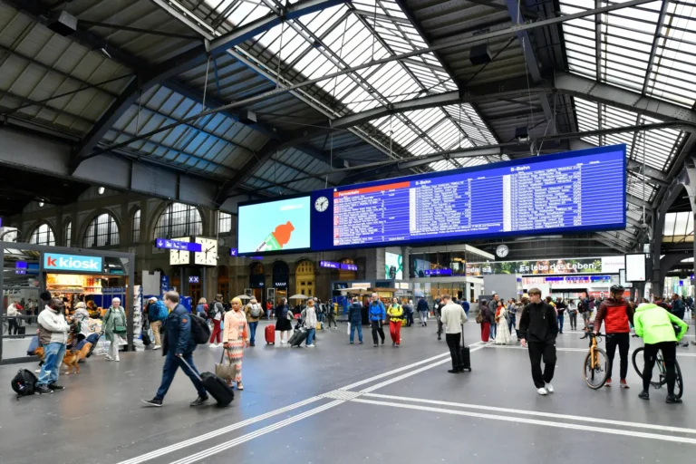 Passengers inside Zurich Main Station (Zürich HB) with departure boards, shops, and connecting rail services across Switzerland and Europe.