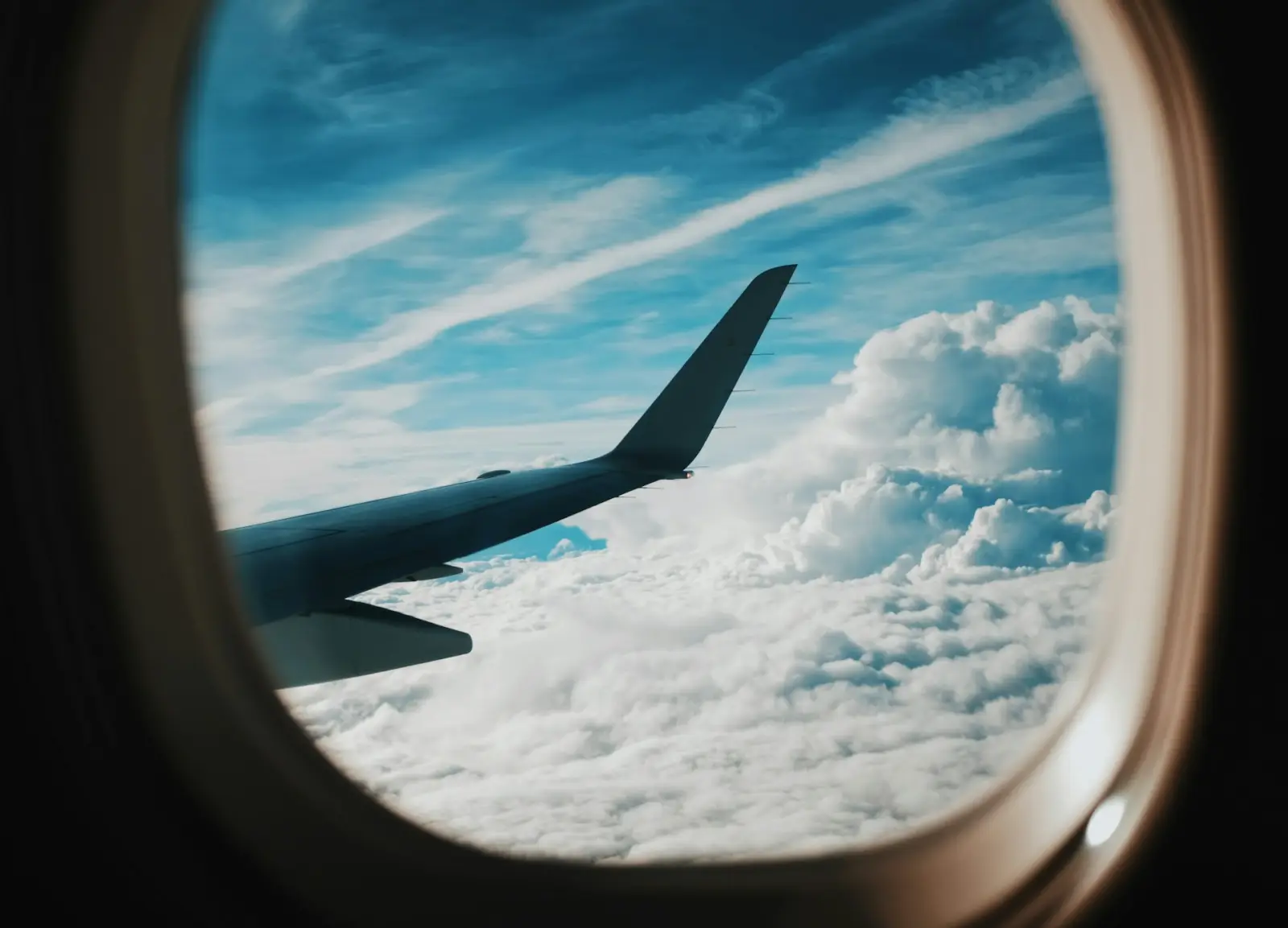 Top 5 International Travel Trends 2025 23 View of an airplane wing and clouds from a passenger window during flight
