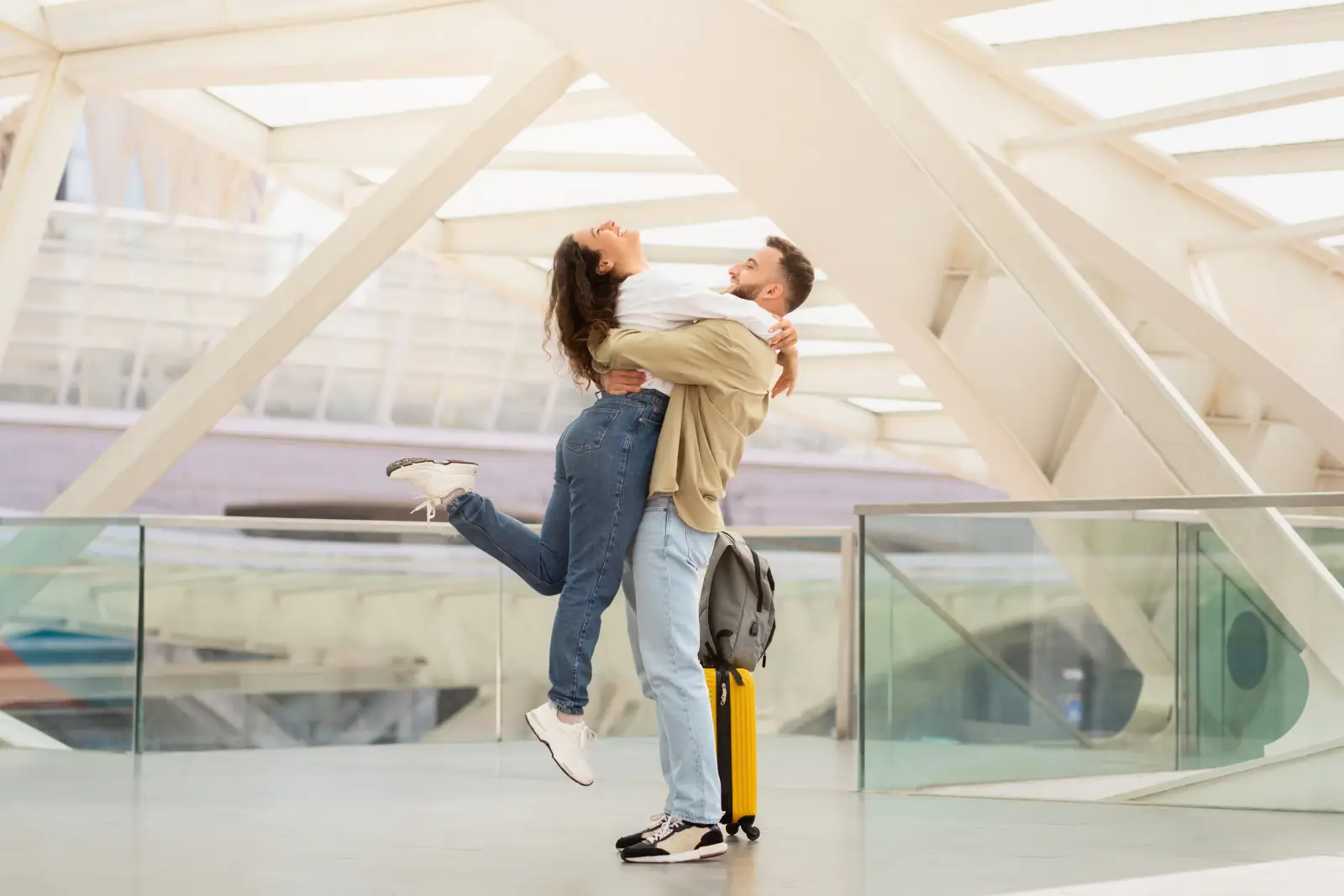 Love In Transit: Airports Where Strangers Become Stories 2 Couple embracing joyfully at an airport terminal with luggage nearby.