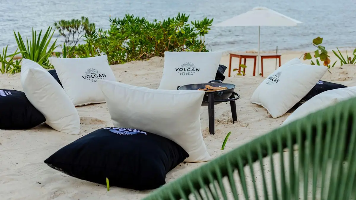 Beach seating with branded pillows and drinks setup at Hilton Cancun’s AMAI Beach Club