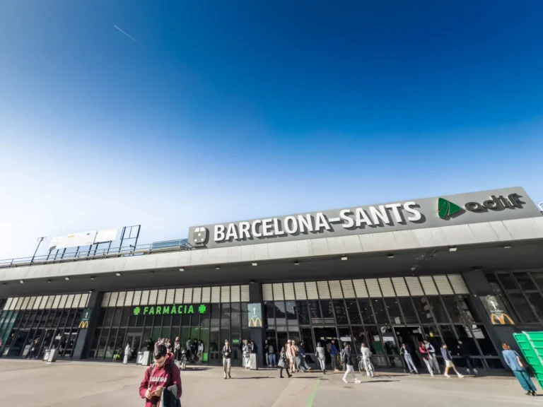 Spain Travel And Tourism News 15 Main entrance of Barcelona Sants train station with ADIF signage and passengers outside.