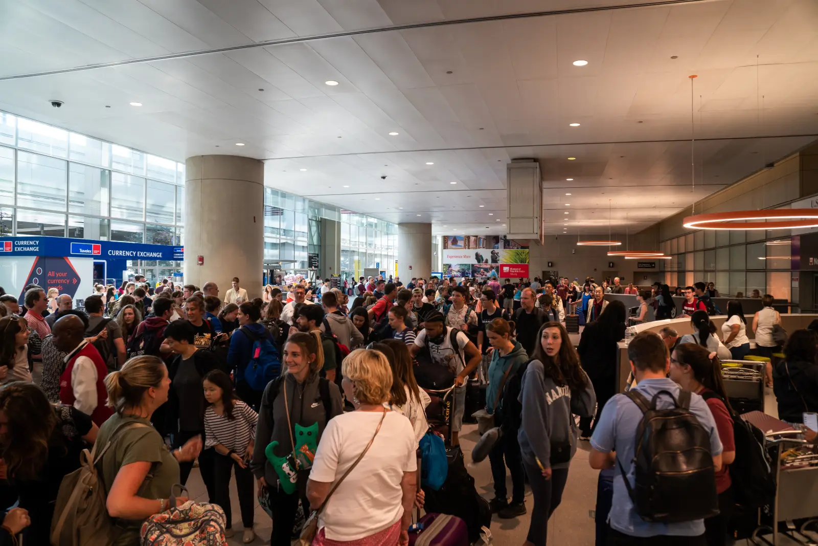 Crowded arrivals hall at Logan International Airport in Boston with passengers waiting and moving through the terminal.