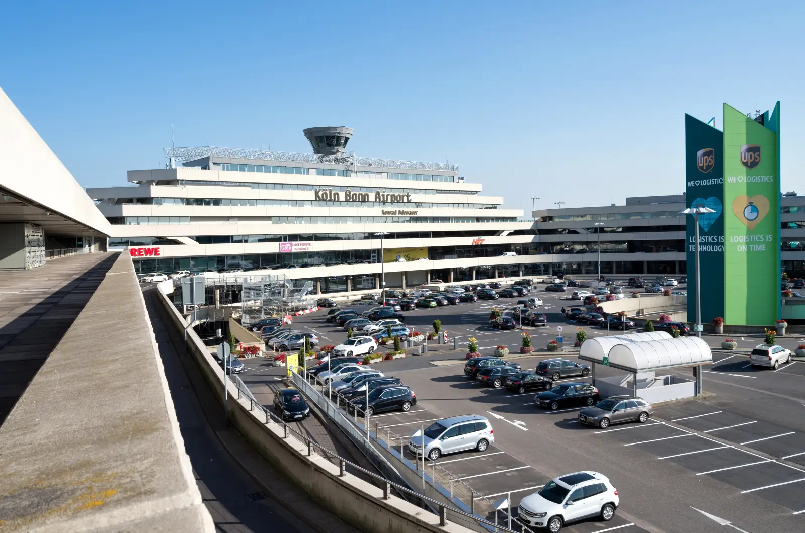 Cars parked in front of Cologne Bonn Airport terminal building on a sunny day in Germany.