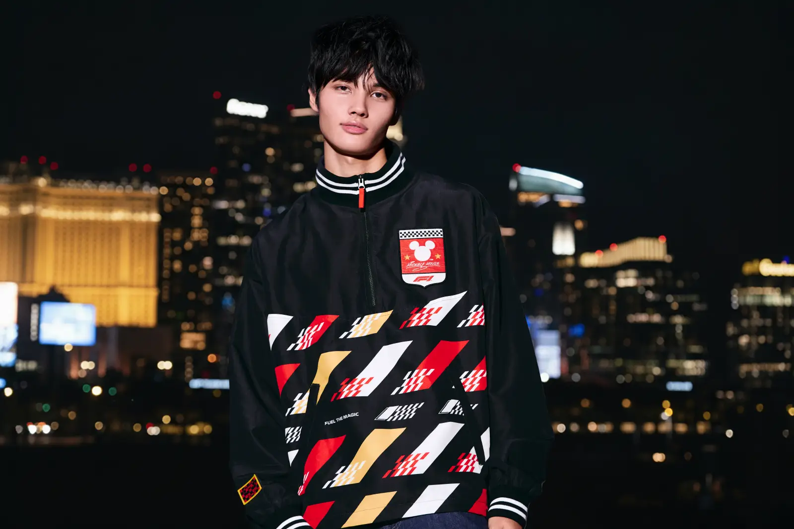 Model wearing Disney x Formula 1 racing jacket at night in Las Vegas