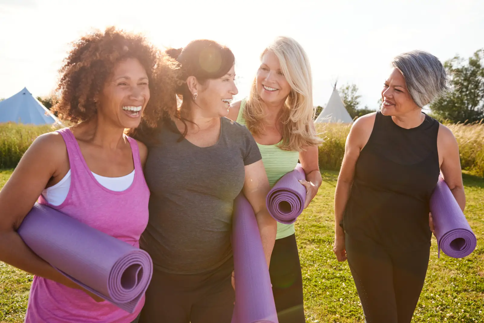 Women’s Health Isn’t One-Size-Fits-All 2 Group of diverse middle-aged women smiling outdoors after yoga class, holding exercise mats