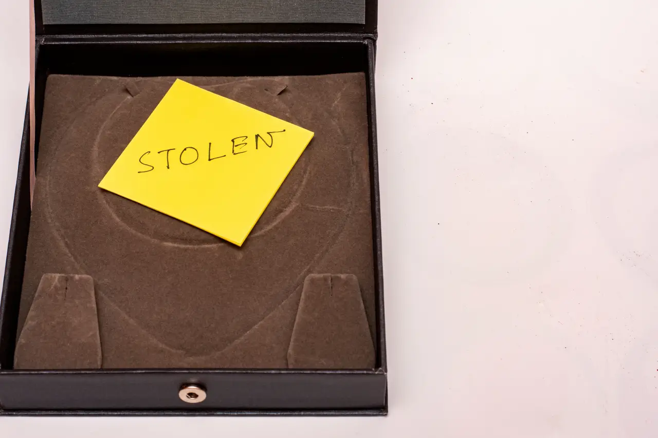Empty jewelry case with a yellow sticky note labeled “stolen,” symbolizing theft or missing valuables.