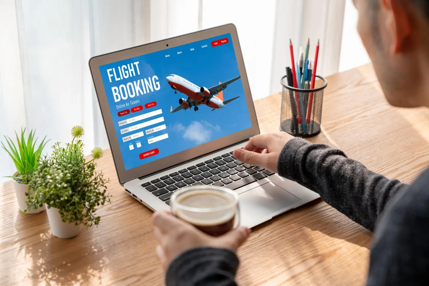 Person booking a flight online on a laptop with a plane image on the screen