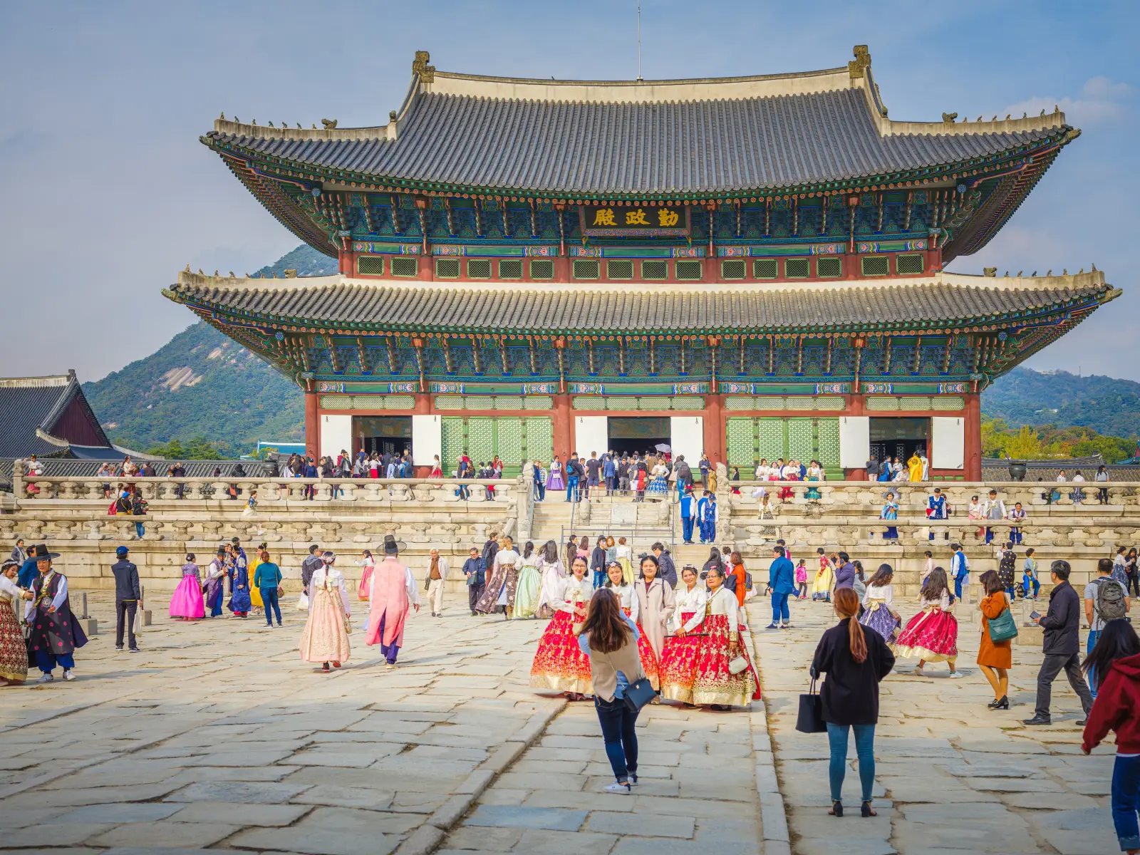 Visitors in traditional hanbok clothing walking around Gyeongbokgung Palace in Seoul, South Korea.