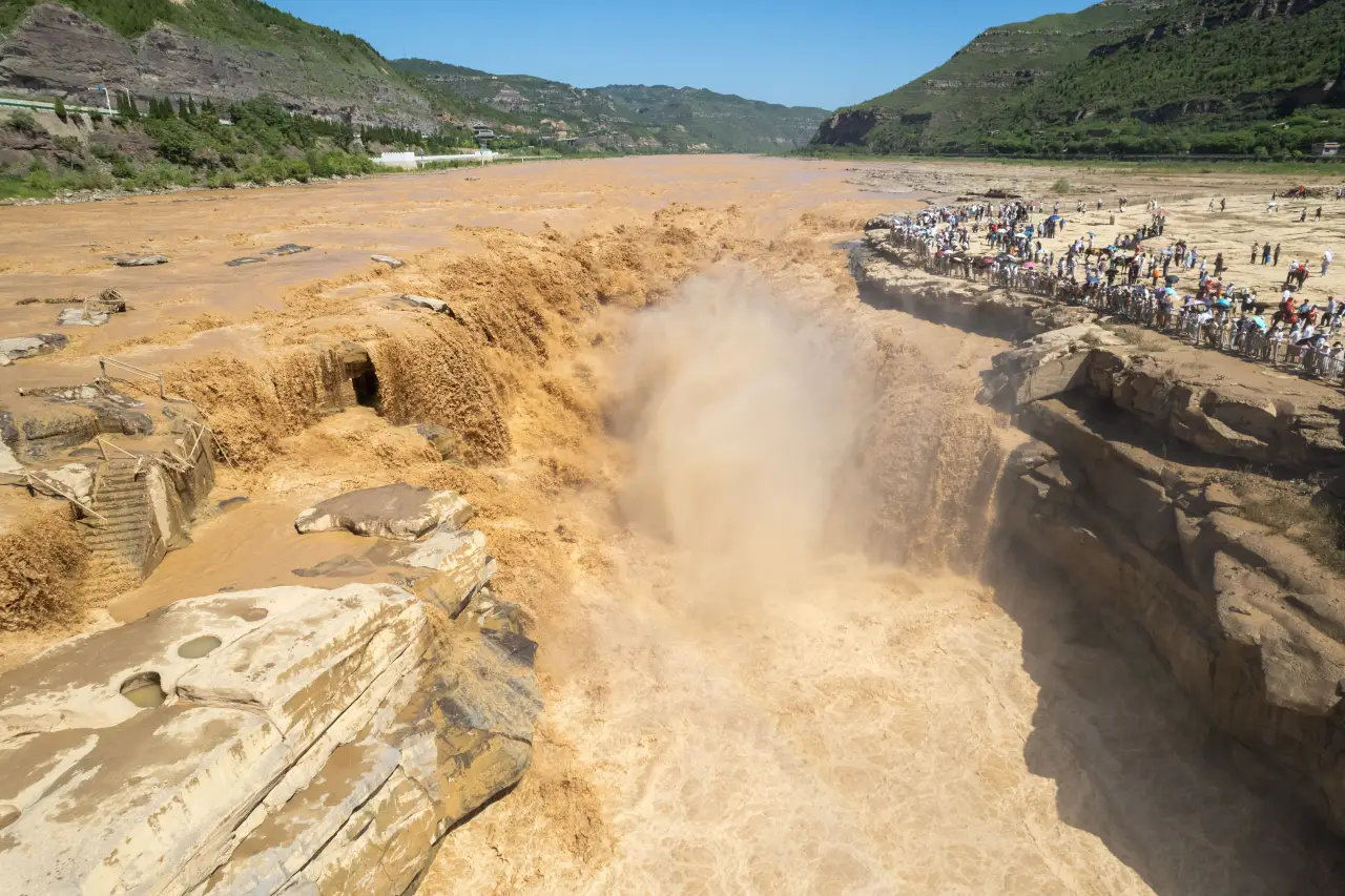 Autumn Rains Turn China’s Hukou Waterfall Into A Roaring Spectacle 2 Tourists watching the powerful flow of Hukou Waterfall on the Yellow River between Shanxi and Shaanxi provinces, China.
