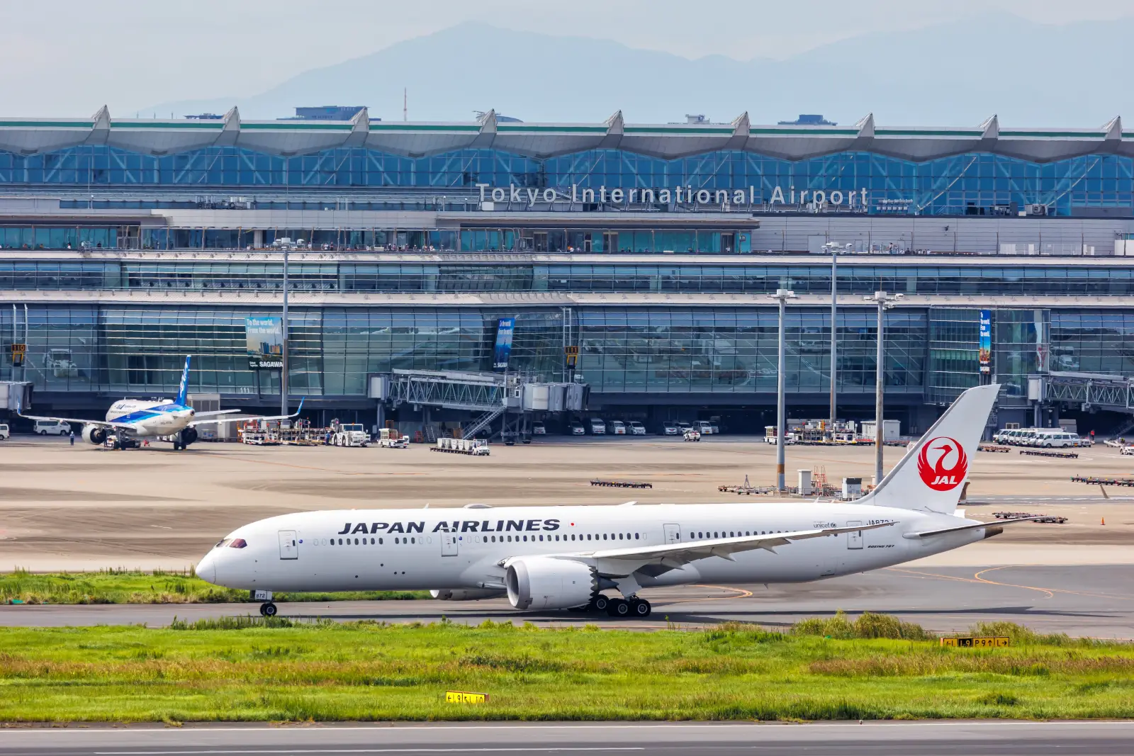 Japan Airlines Boeing aircraft taxiing at Tokyo International Airport with terminal in the background