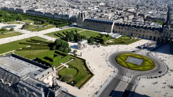 Home 9 Aerial view of the Louvre Museum and the surrounding gardens in Paris, featuring the Arc de Triomphe du Carrousel and manicured pathways.
