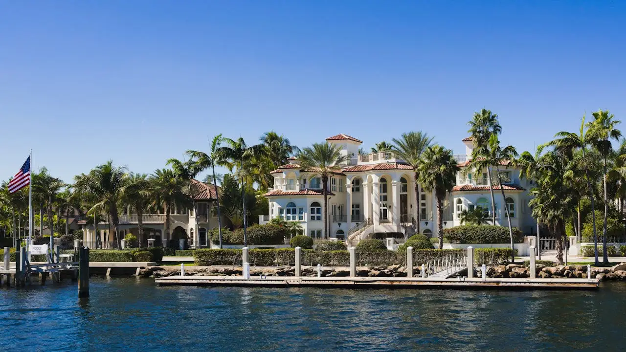 What To Look For In Family-Friendly Vacation Homes 3 Luxury waterfront vacation home with palm trees and private dock under a clear blue sky.