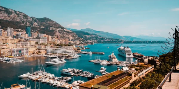 Home 1 Monaco harbor with luxury yachts, cruise ships, and city buildings along the Mediterranean coast