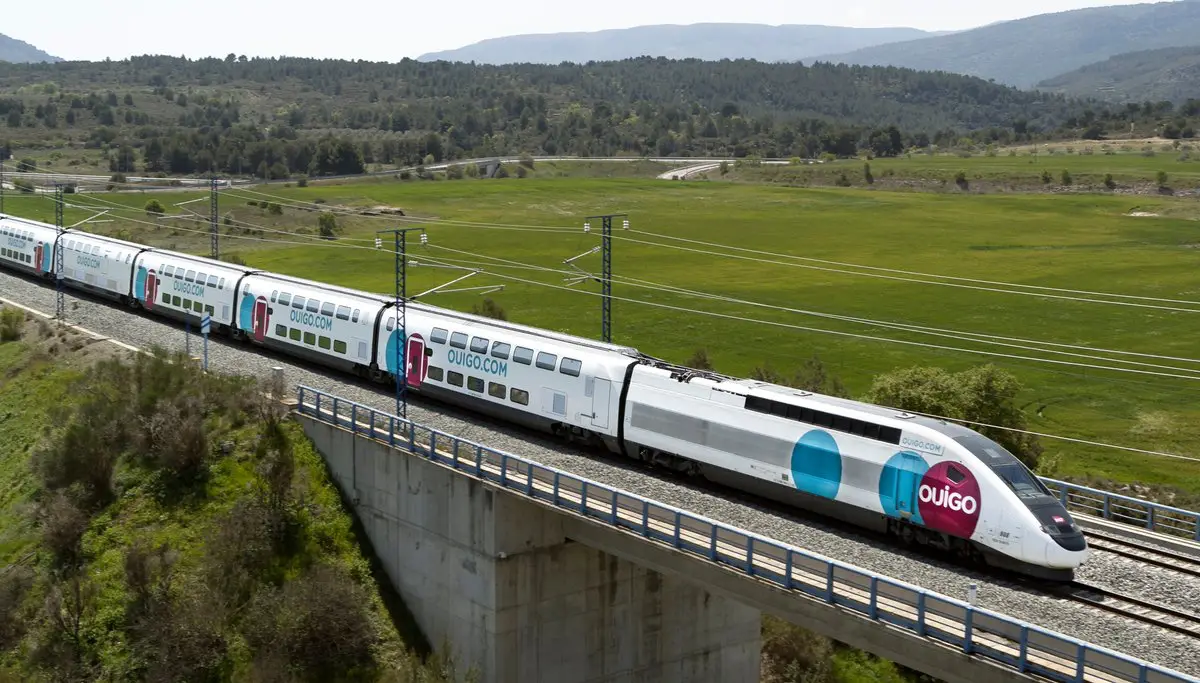 Ouigo high-speed double-decker train traveling through the Spanish countryside on an elevated track