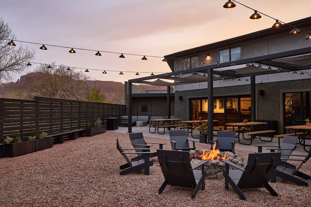 Hilton Expands Lifestyle Portfolio With Launch Of New Brand - Outset Collection By Hilton 3 Outdoor fire pit and seating area at a future Outset Collection by Hilton hotel in Moab, Utah, surrounded by desert scenery at sunset.