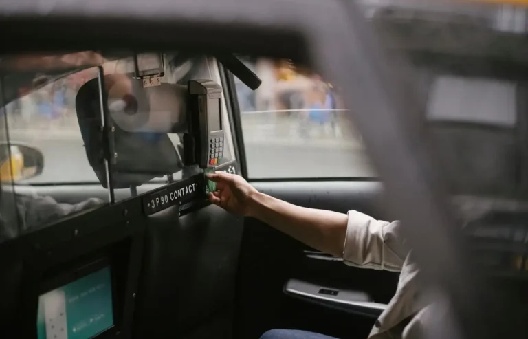 Person paying for a taxi ride using a credit card machine inside the cab.