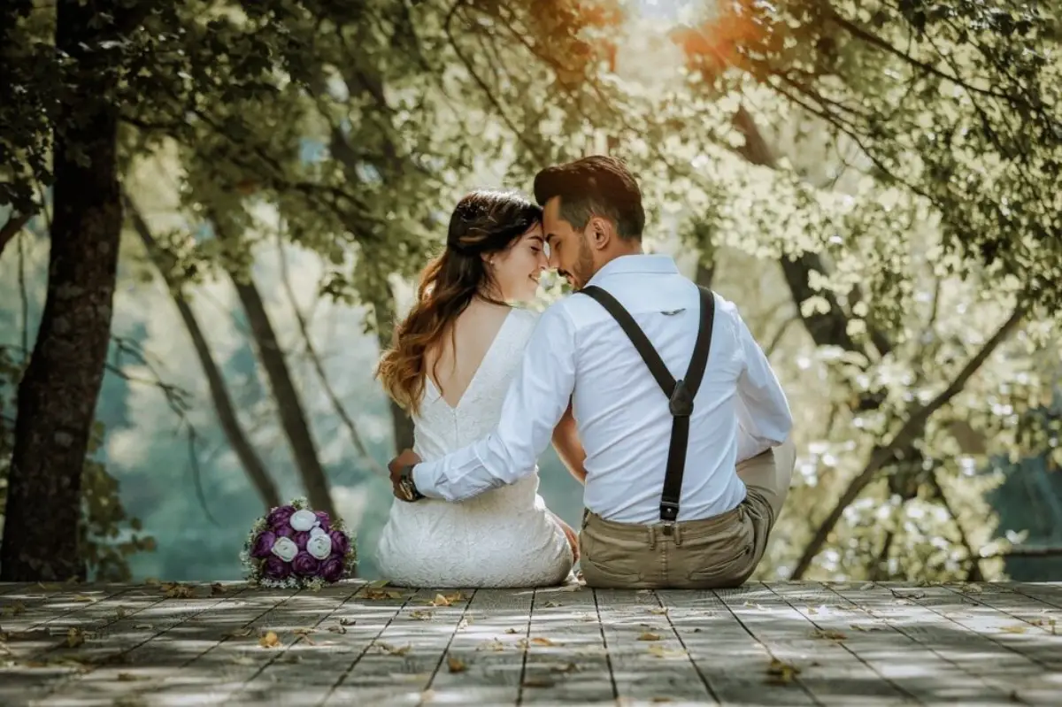 What The Best Woman to Marry by Country 22 Bride and groom sit close together on a wooden deck in a forest setting