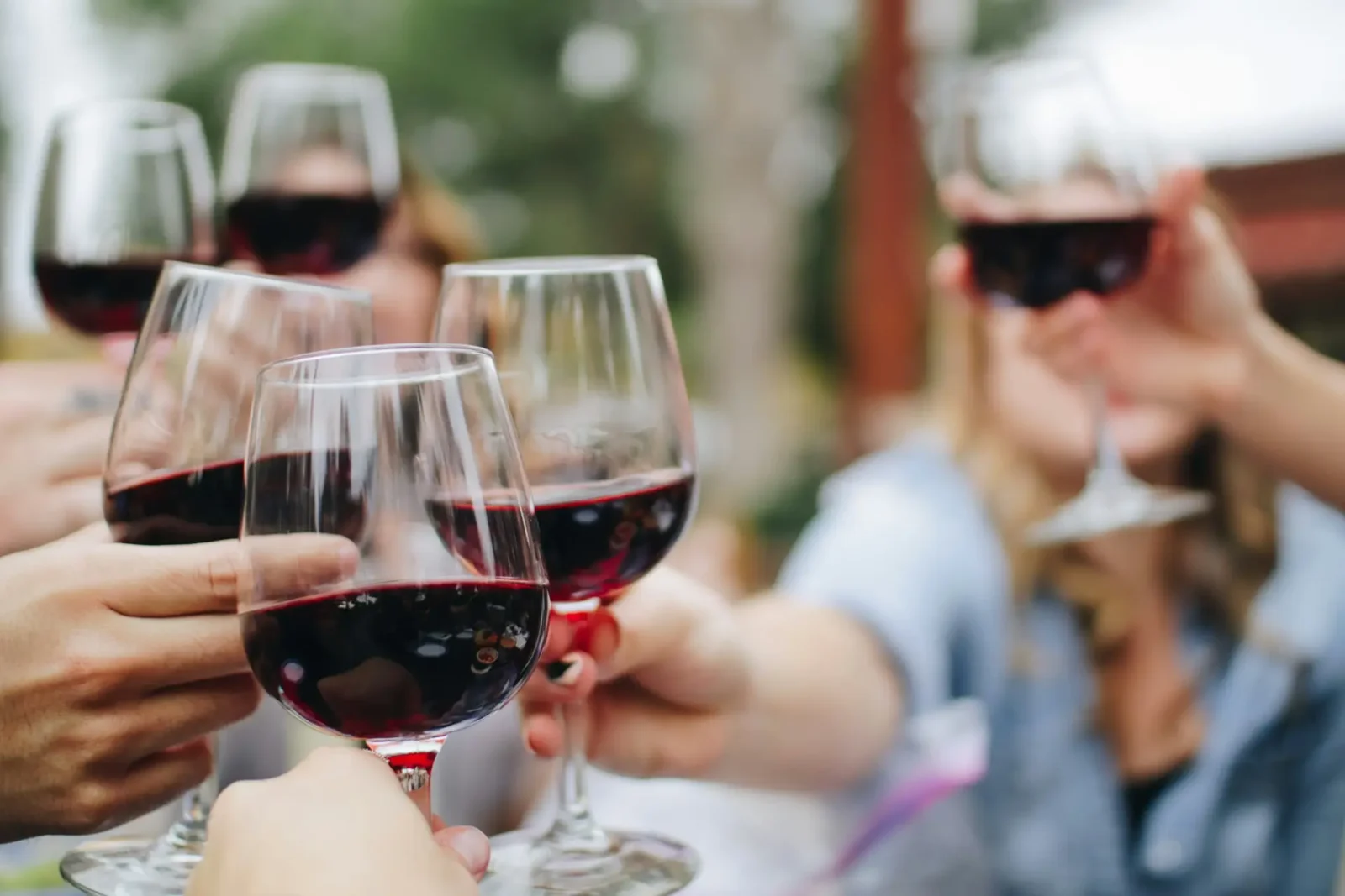 Group toasting with glasses of red wine during a relaxed outdoor gathering