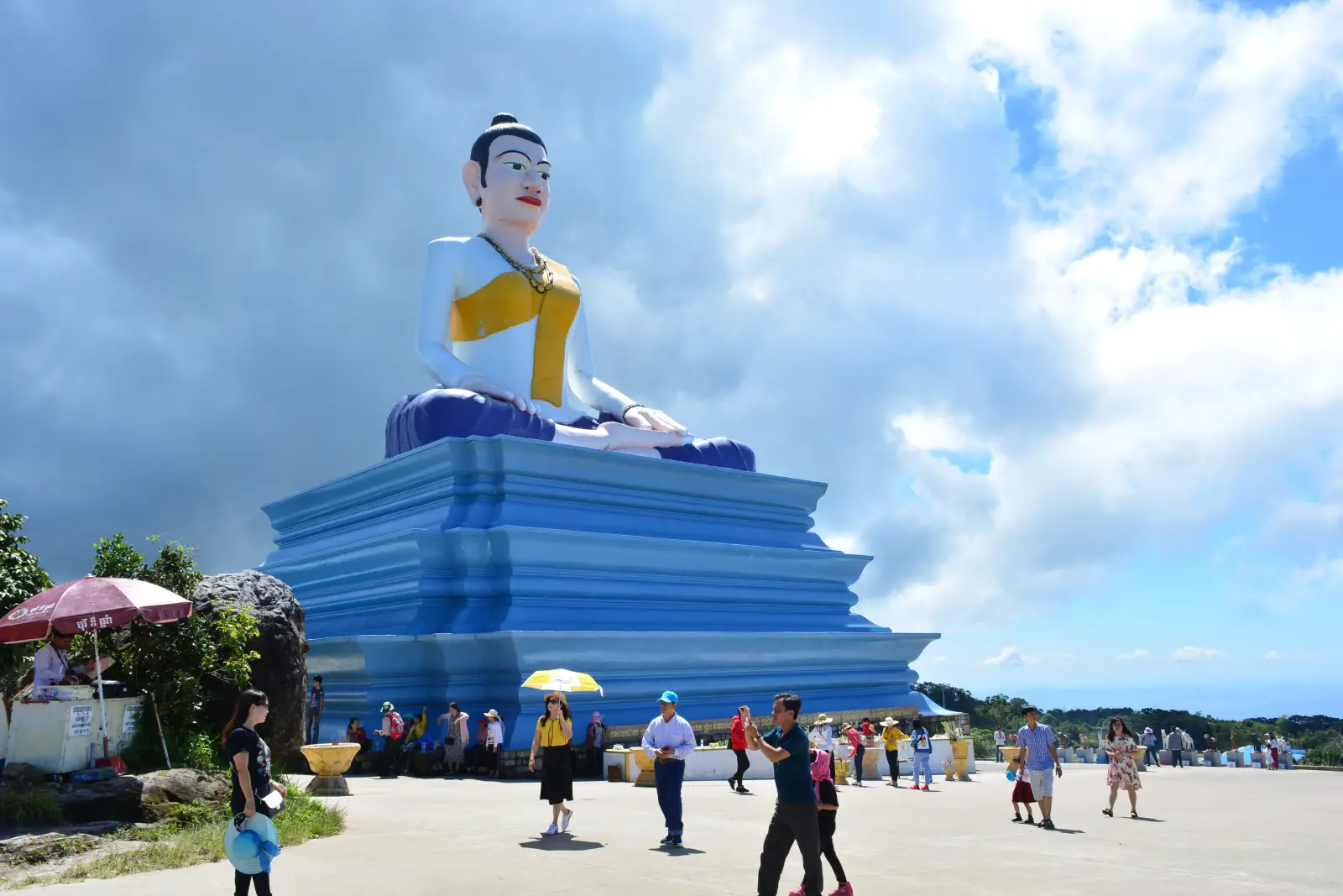 Tourists visiting the Ya Mao monument at Bokor National Park in Kampot, Cambodia, under a partly cloudy sky.