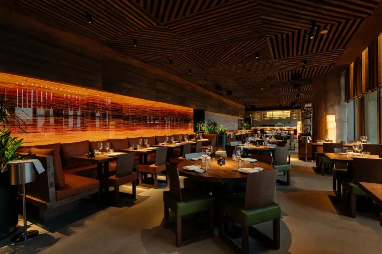 Elegant interior of a Zuma restaurant with warm lighting, wooden decor, and neatly set dining tables.