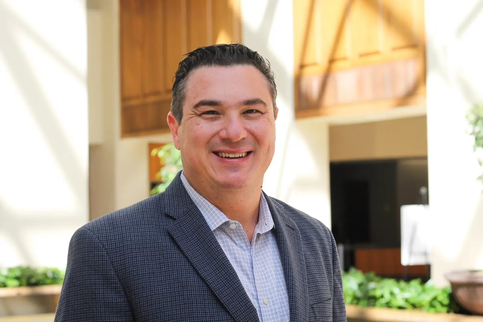 Portrait of Baris Agacbuken smiling in a bright hotel lobby.