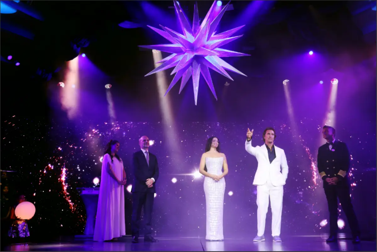 Camila and Matthew McConaughey stand on stage under a glowing star installation during the Star Princess naming ceremony.