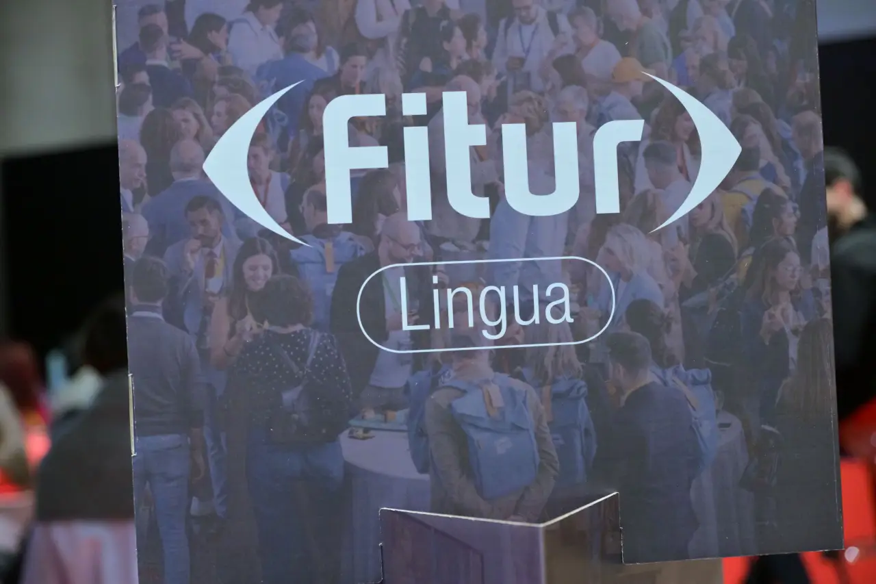 Sign for FITUR Lingua in front of a crowd at a tourism event.