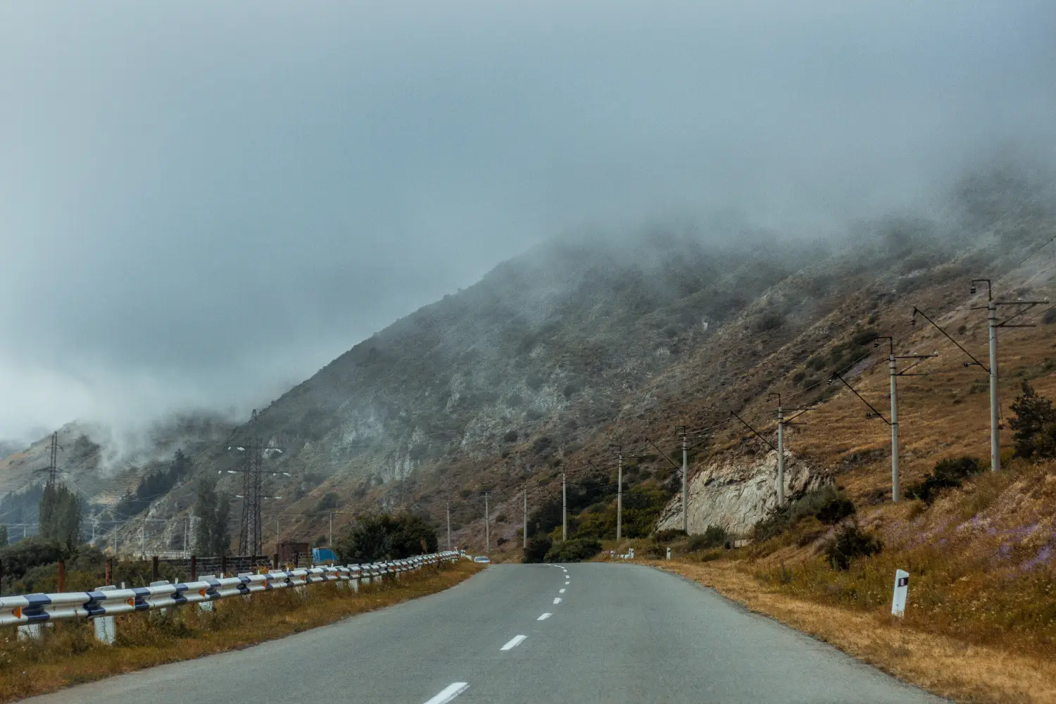 Whеn Evеry Trip Bеcomеs A Story: How Crеators Capturе Journеys Today 2 Fog-covered mountain road with guardrails and utility poles along a winding rural route