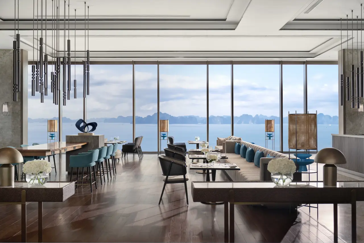 Elegant hotel lounge with floor-to-ceiling windows overlooking Ha Long Bay’s limestone islands.