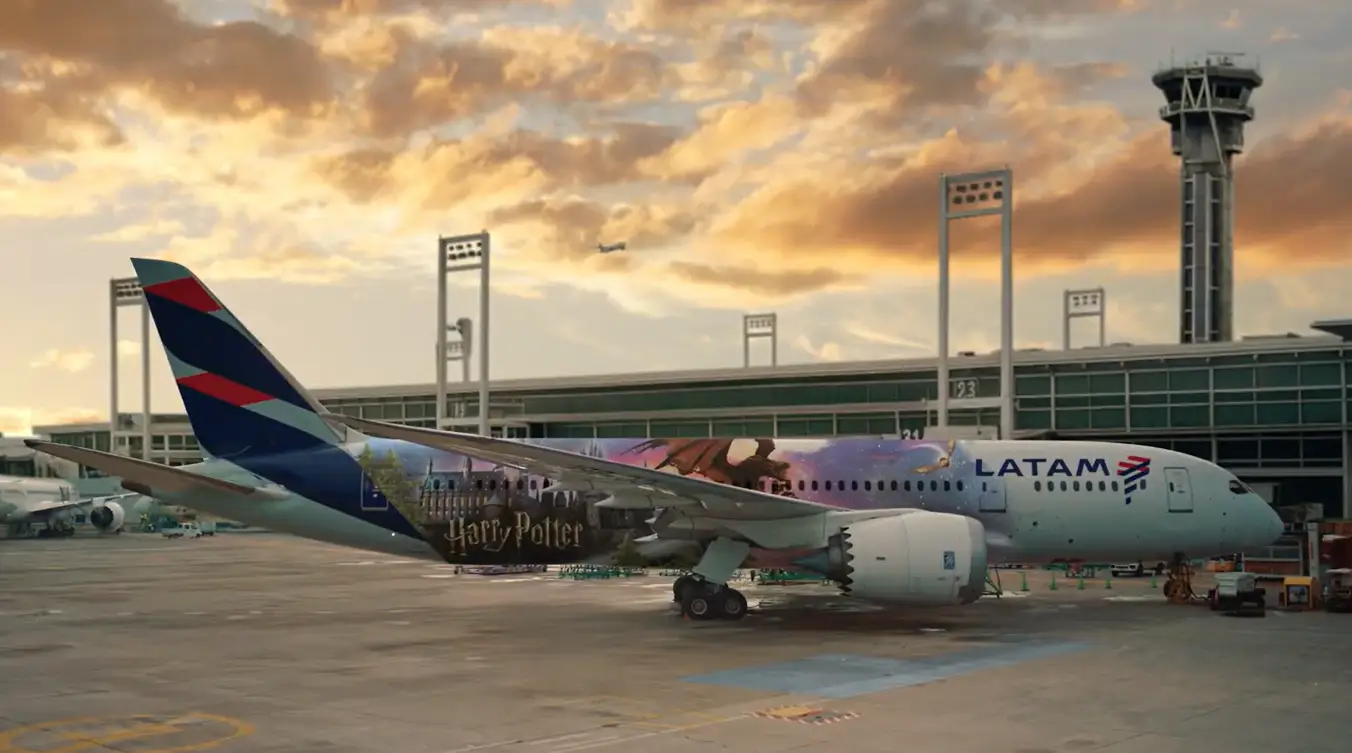 LATAM Boeing 787-9 aircraft featuring Harry Potter-themed livery parked at an airport during sunset