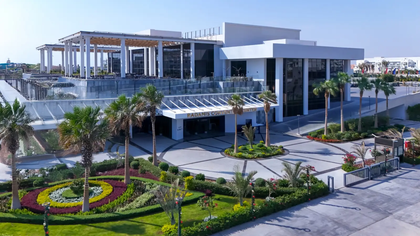Modern exterior view of the Radamis Convention Center surrounded by landscaped gardens and palm trees.